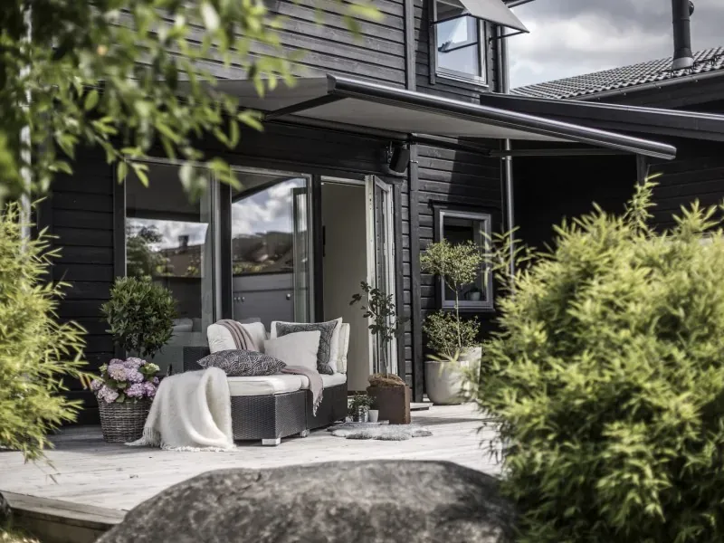 Uteplats med terrassmarkis på ett svart trähus