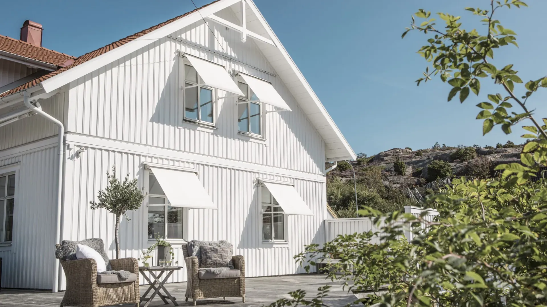 Vitt trähus med ljusa fönstermarkiser
